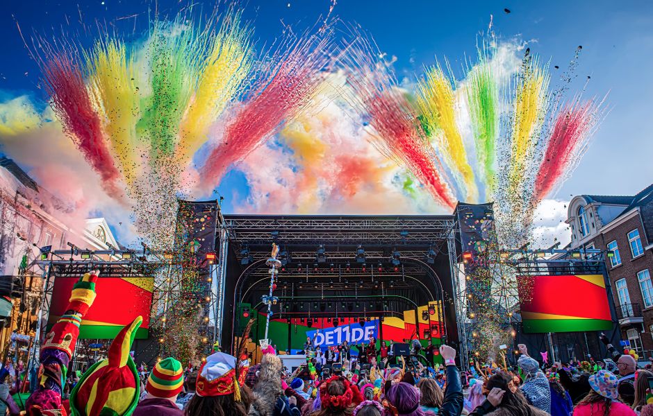 Carnavalspodium met kleurrijke confettikanonnen en feestend publiek