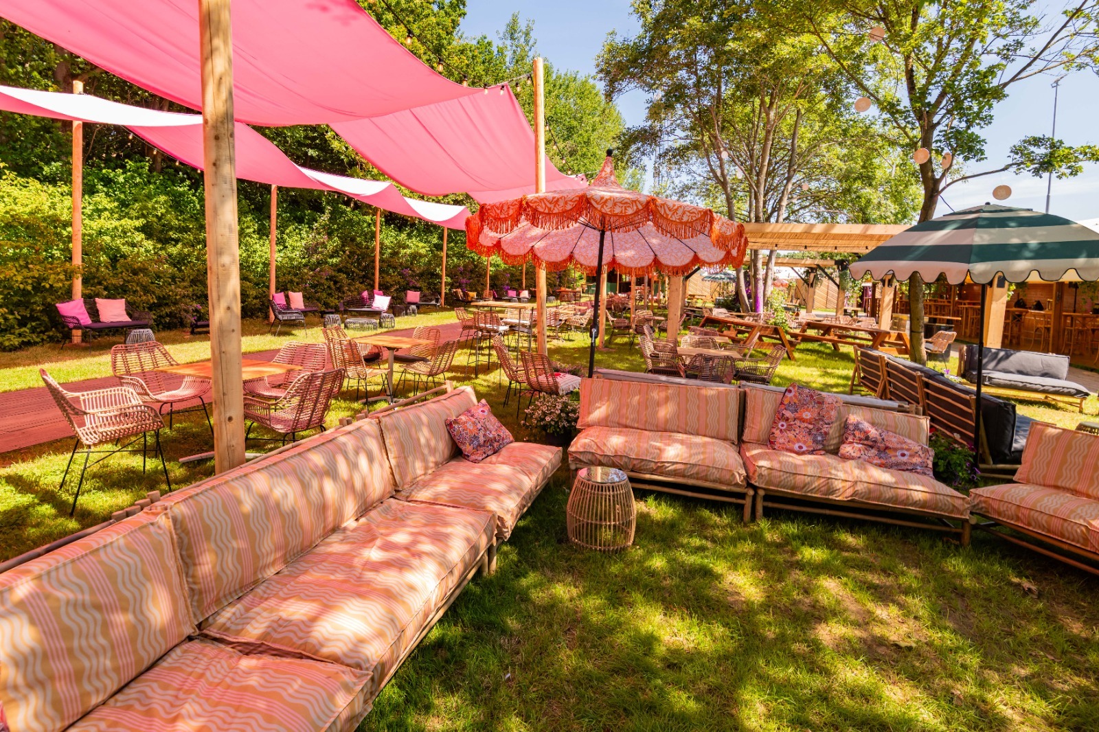 Pinkpop lounge met roze schaduwdoeken, parasols en gestoffeerd loungemeubilair
