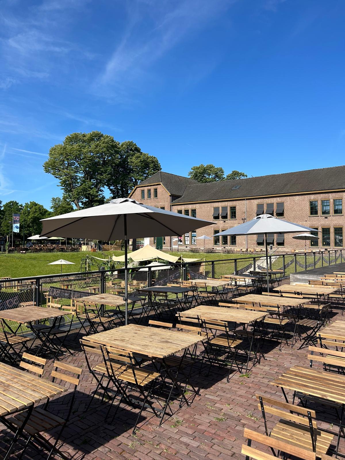 Overzicht van het terras met parasols en houten meubilair