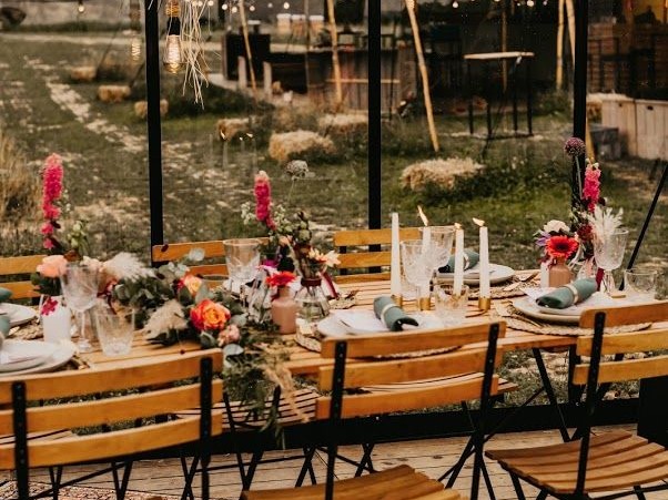 Gedekte bruiloftstafel met bloemen en kaarslicht onder een glazen tent
