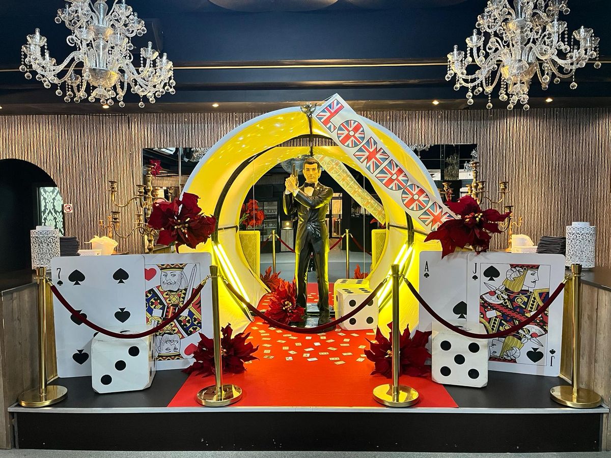 Casino-themafeest met James Bond-beeld, kaartdecors, dobbelstenen en rode loper