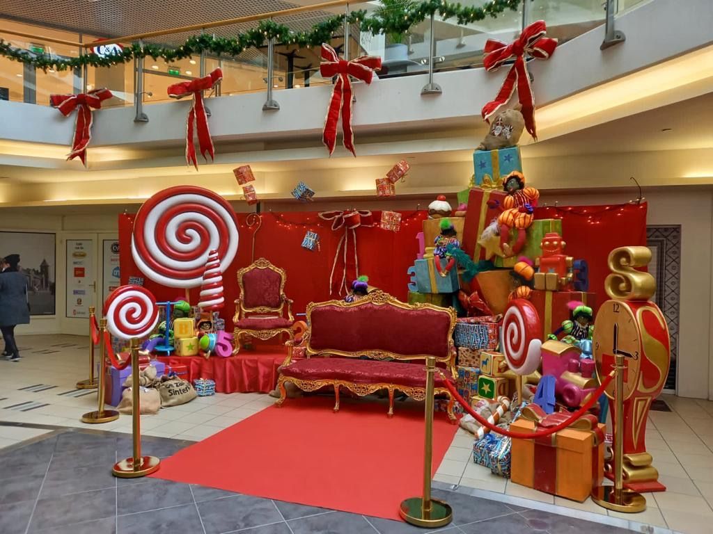Sinterklaasdecoratie met stuitchair, cadeaus, lolly's en rode loper in een winkelcentrum