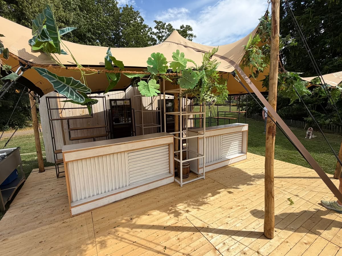 Modulaire barren op een houten dek onder een stretchtent, gedecoreerd met groen