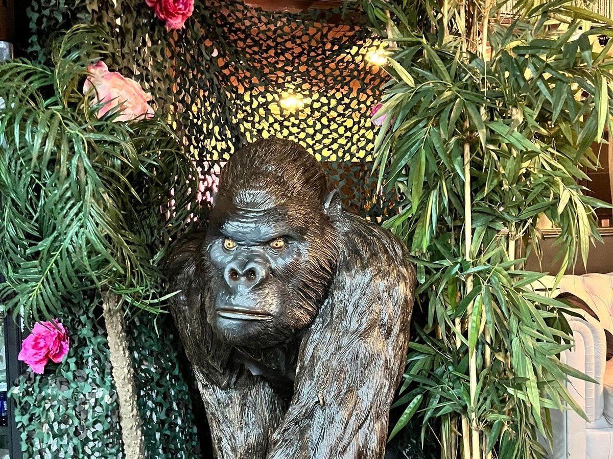 Levensgrote gorillabeelden tussen bamboe en camouflagenet als jungledecor