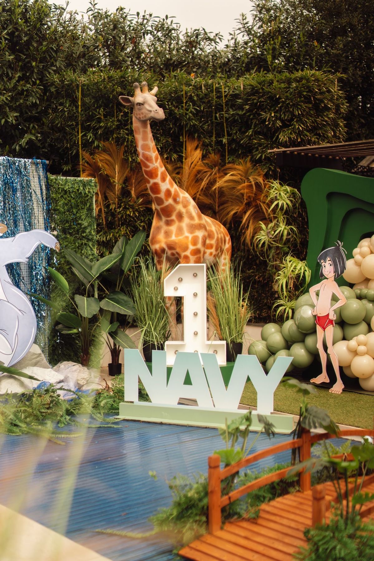 Jungle-themafeest met giraffenbeeld, lichtcijfer, ballonnen en groendecor