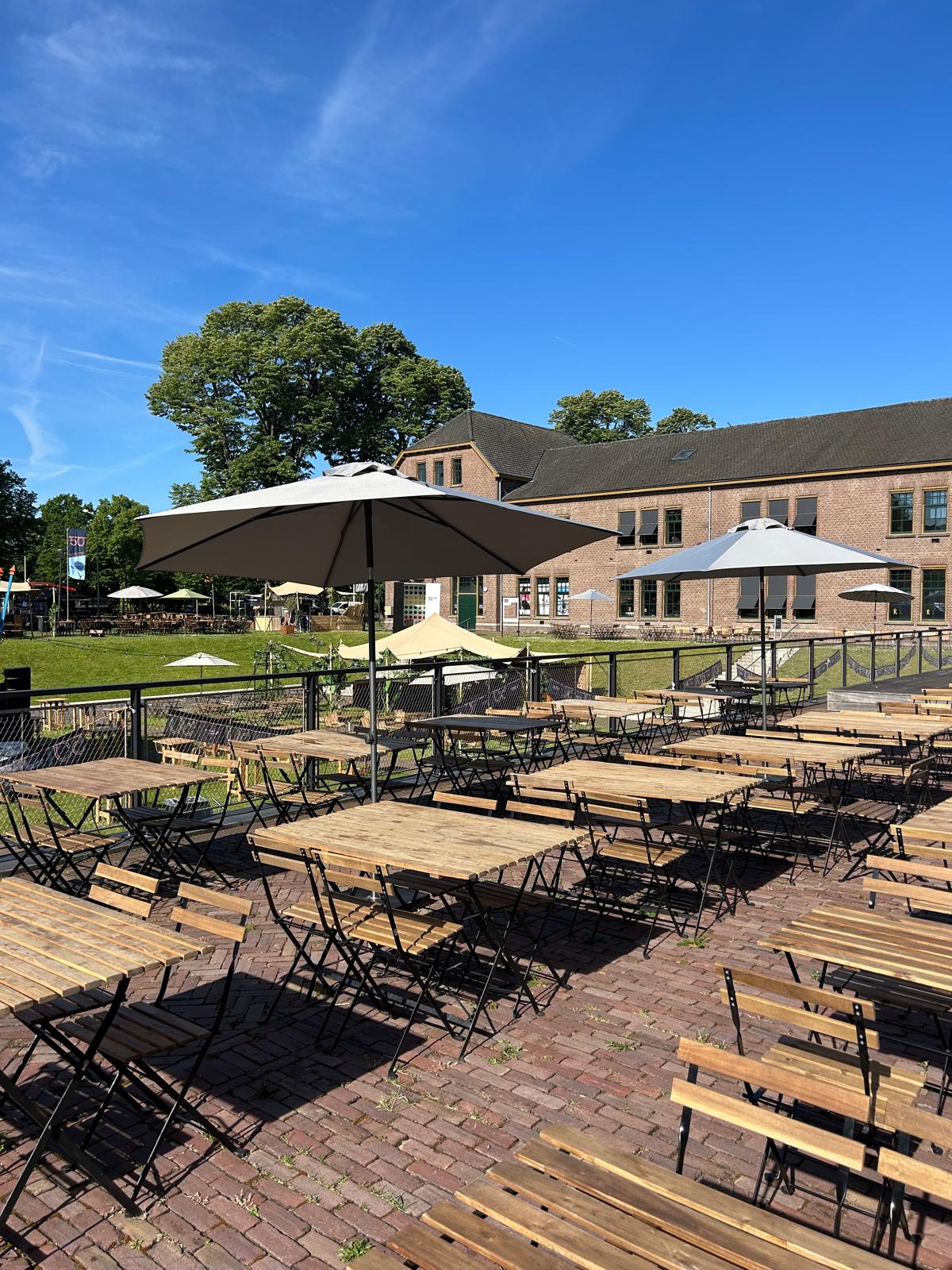 Terras met houten klaptafels en stoelen voor de Tapijnkazerne