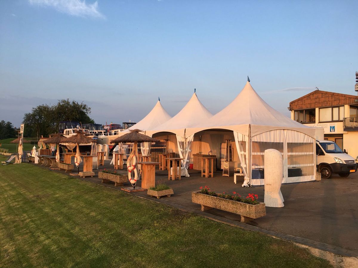 Witte pagodetenten met houten barren op een evenemententerrein bij zonsondergang