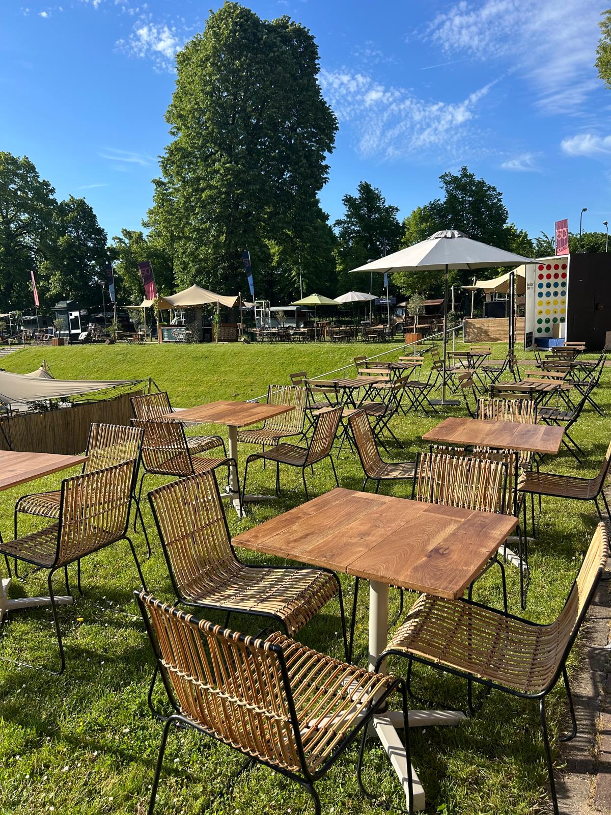Terras met houten tafels, rotan stoelen en parasols