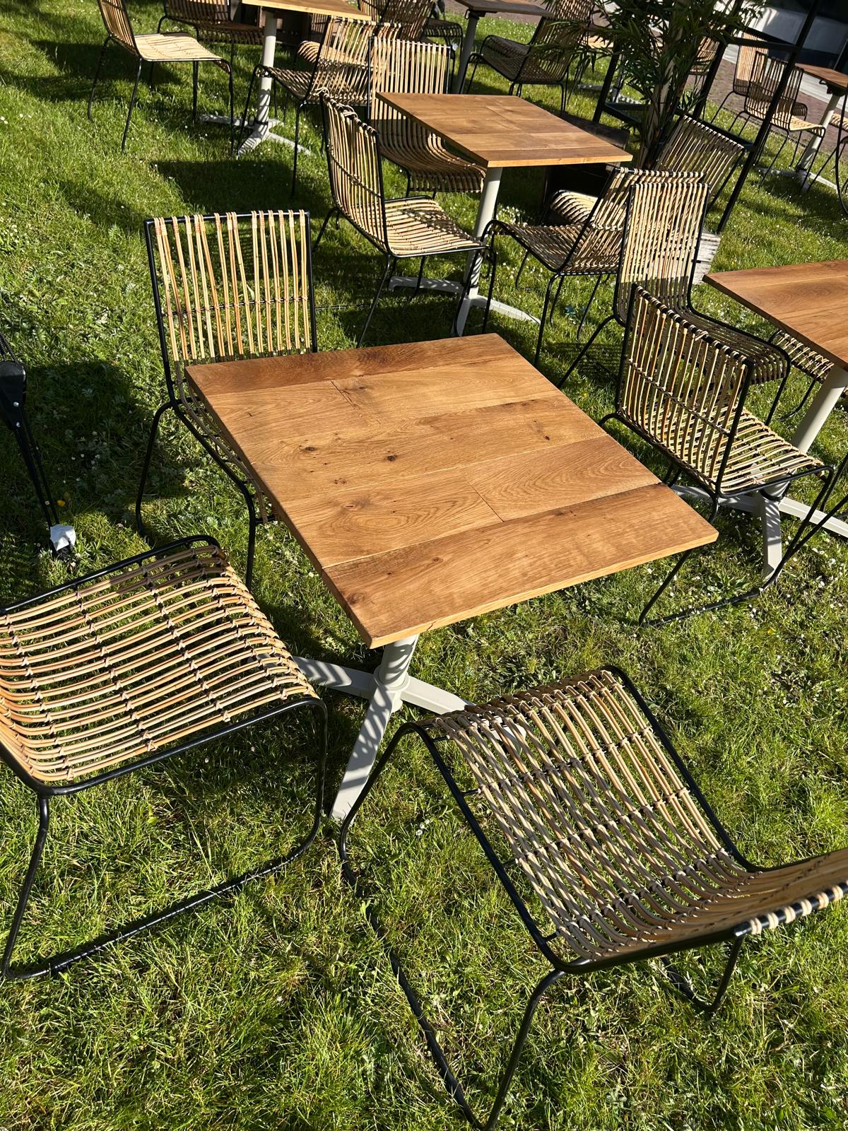 Houten terrastafel met rotan stoelen op het gras