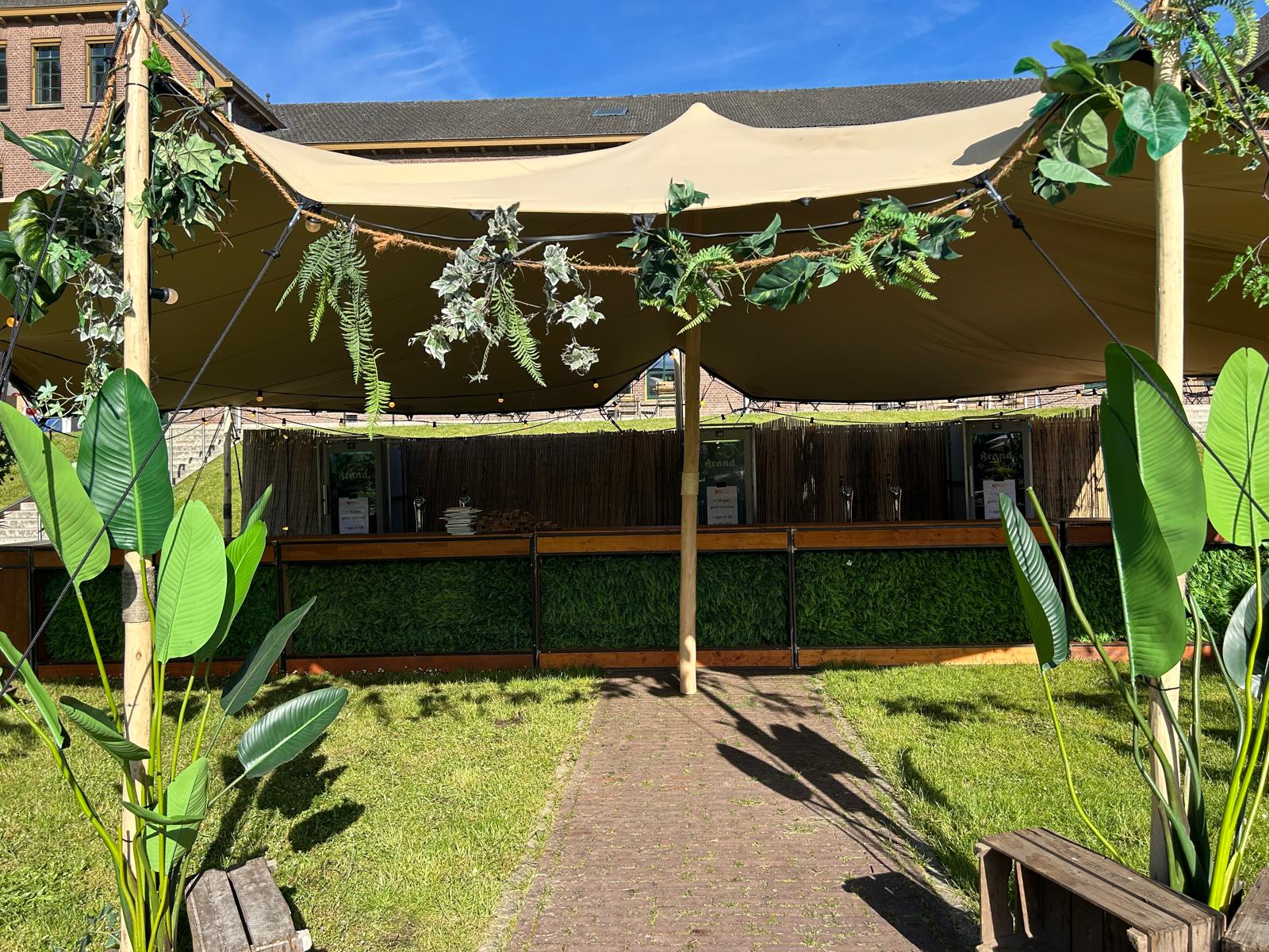 Bar onder een stretchtent met tropische groendecoratie