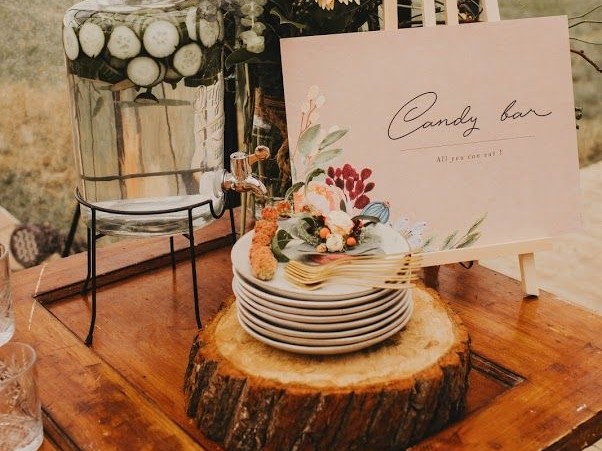 Tafelstyling met drankdispenser, borden op houten schijf en candy bar-bordje