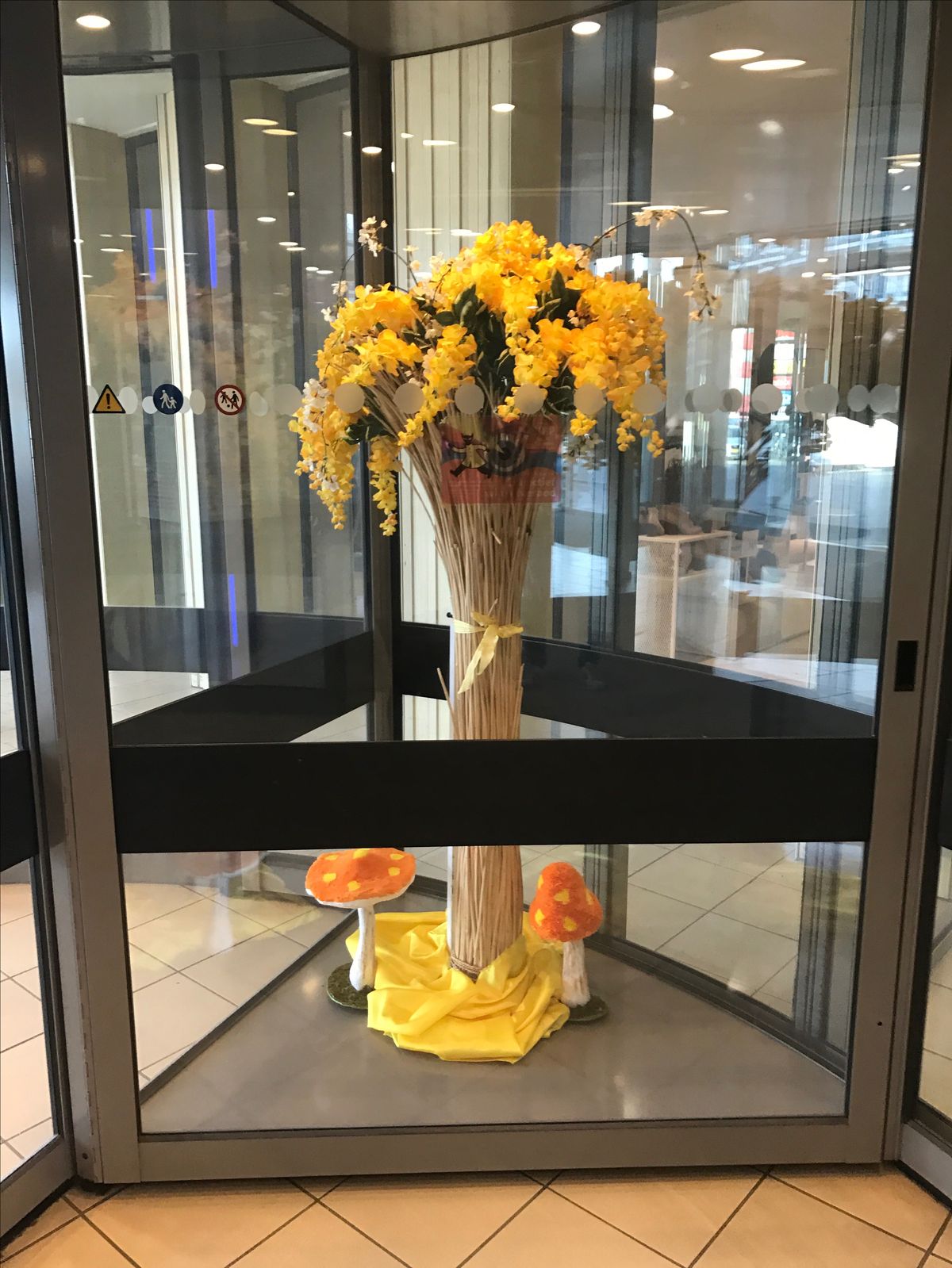 Bloemendecoratie met gele orchideeën in de roterende inkomdeuren van een winkelcentrum