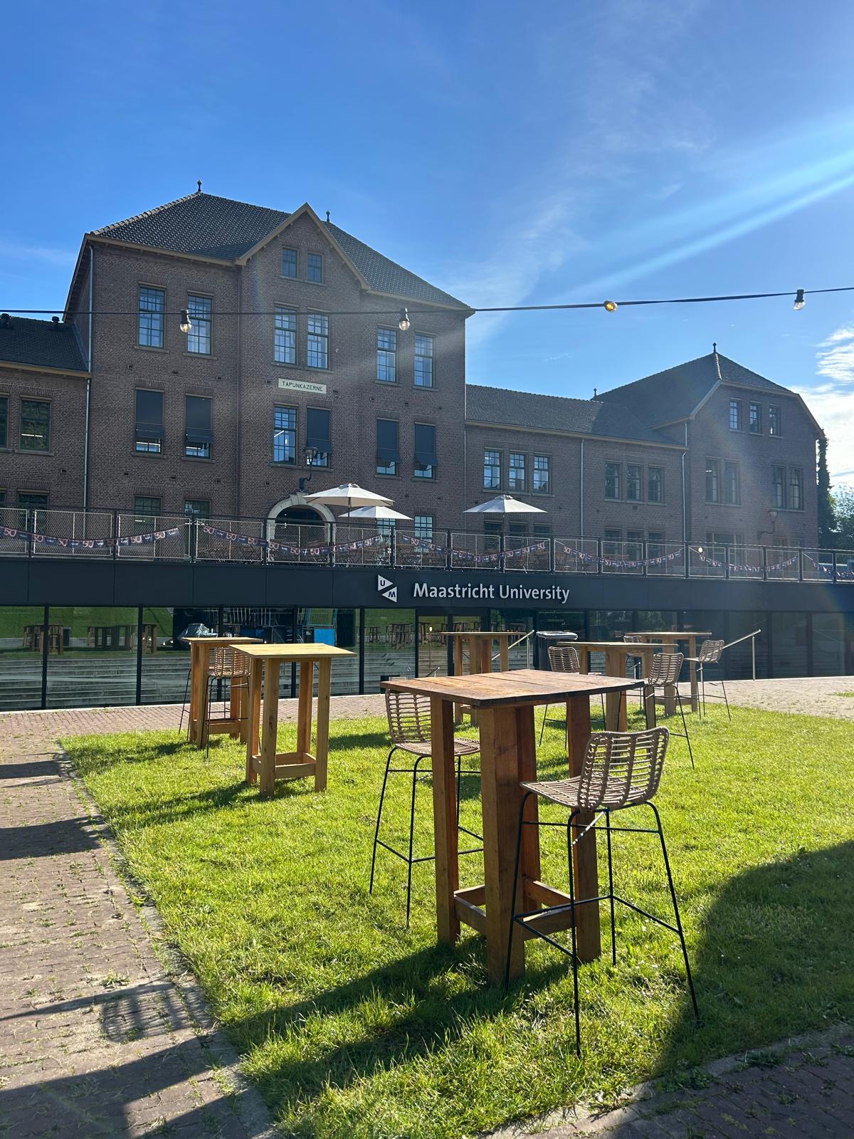 Hoge tafels en barkrukken voor het gebouw van Universiteit Maastricht