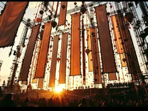 Hoog festivaltoneel met hangende banners en lantaarns, crew installeert decoraties met ladders tijdens gouden uur